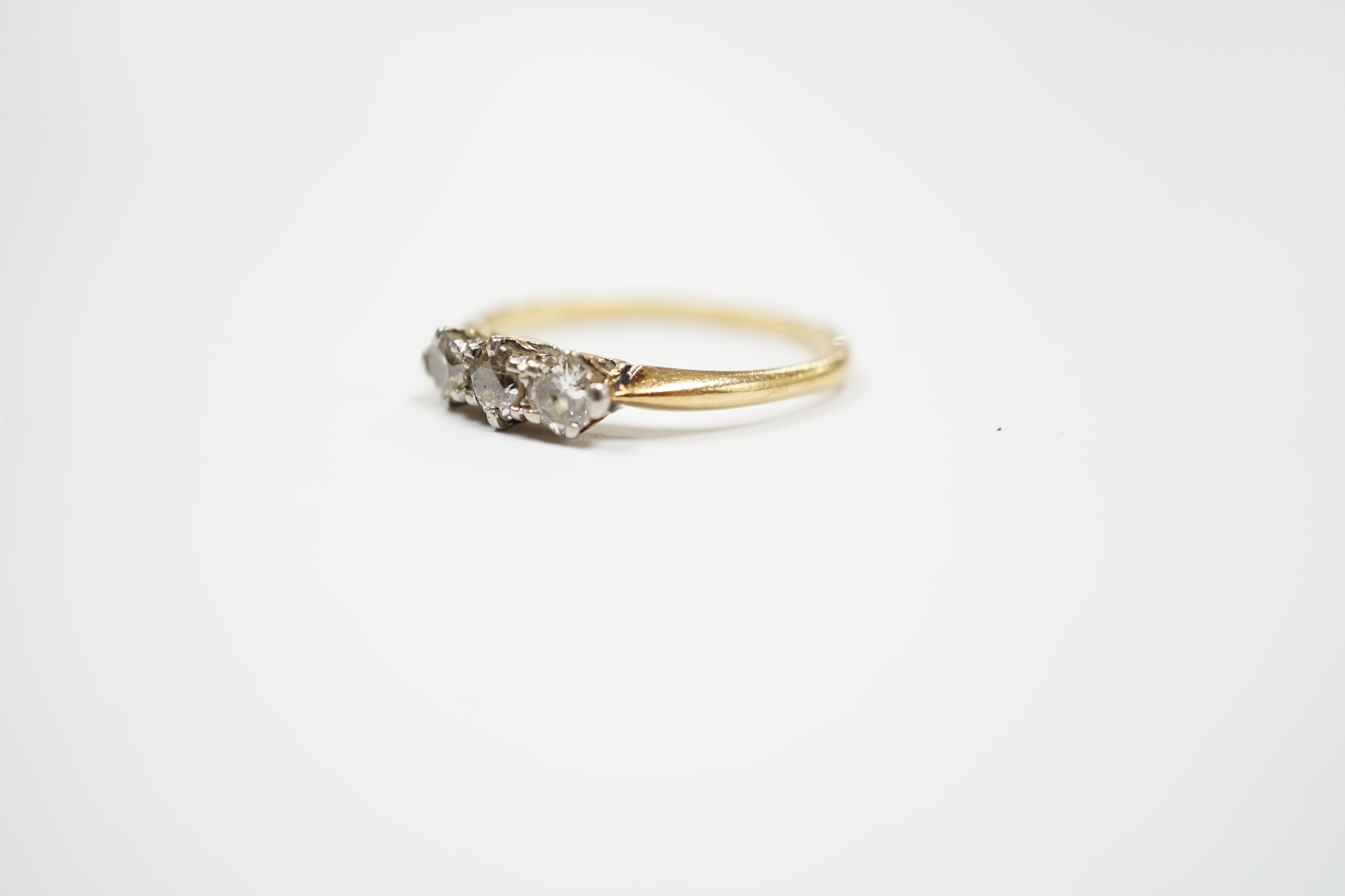 A yellow metal and three stone diamond set ring, size M, gross weight 2.3 grams.